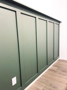 an empty room with green painted walls and wood flooring on the wall, along with a wooden floor