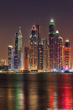 the city skyline is lit up at night with bright lights on it's skyscrapers