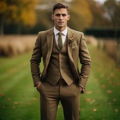 a man in a suit and tie standing on the grass with his hands in his pockets