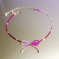 a pink and white beaded necklace on a table