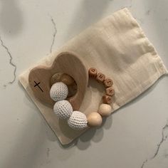 a wooden pacifier with two balls in it on top of a cloth bag next to a pair of scissors