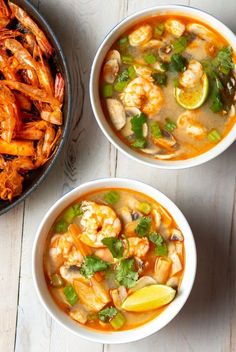 two bowls of shrimp and vegetable soup on a table