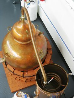 an old fashioned tea kettle sitting on top of a wooden table next to a cup