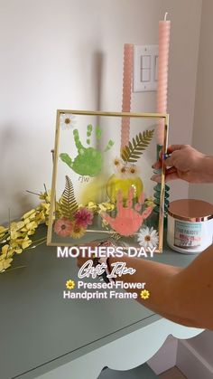 a woman is decorating a mothers day card with flowers and handprints on it