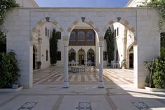 an outdoor courtyard with columns and arches in the middle, surrounded by greenery on both sides