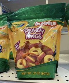 two bags of peach rings sitting on a shelf in a store, one bag is filled with fruit