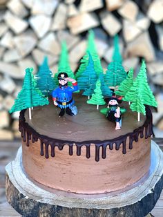 a chocolate cake with frosting and decorations on top, sitting on a wooden table