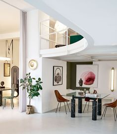 a dining room table with four chairs and a spiral stair case in the back ground