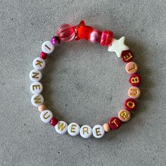 a close up of a beaded bracelet on the ground with words written across it