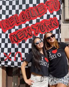 two girls standing next to each other in front of a sign