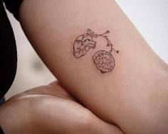 a small tattoo on the leg of a woman's left thigh, with an outline of a brain and heart