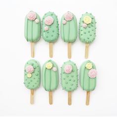 some green and pink desserts with flowers on them are arranged in the shape of cactuses