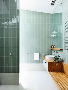 a bathroom with green tile and wooden flooring