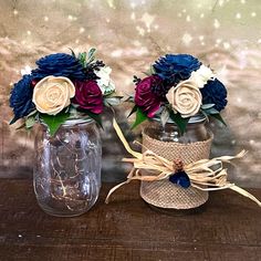 two vases with flowers in them sitting on a wooden table next to each other