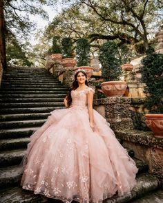 a woman in a pink dress standing on some stairs