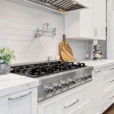 a stove top oven sitting inside of a kitchen next to white cabinets and counter tops