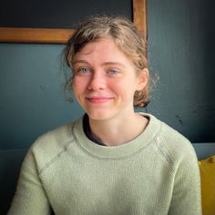 a woman sitting in front of a window smiling