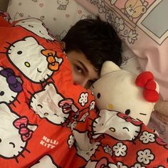 a person laying in bed with a hello kitty comforter