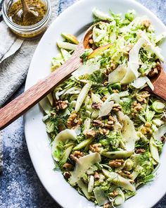 a white plate topped with broccoli salad next to a wooden spoon on top of a table