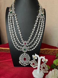 Grand Haram AD Diamond Ruby Emerald Doublet Stone/Bridal Haram/34 Inches Long Haram Ruby Stone/ Detachable pendant /South Indian jewelry This item is perfect for parties and festivals!  ITEM DETAILS: Handmade jewelry  Includes One Long Haram and Two Earrings. Necklace: 34.0 inches.total 34 inches long Wide 2.9 Pendent   Adjustable length. chain closure. Weighs 6.66oz (105 g).  Earrings:2.8 inch(es) long. Earring set weighs 0.75 oz (188g). Earring backs push on/off. Material: Imitation Micro gold, pearls Drop and. AD Stones. Finish: Premium Gold GJ Dimond Finish.  NOTE: I try my best to show you photos of my products as they appear in real life, but please note that variations in color occur due to differences in lighting and screen settings.  PRODUCT CARE: - Avoid contact with heat/fire, w Luxury Ruby Chandbalis In Temple Jewelry Style, Luxury Ruby Temple Necklace With Tilla, Detachable Pendant, Long Haram, Long Earring, South Indian Jewelry, Ruby Emerald, Ruby Stone, Pearl Drop