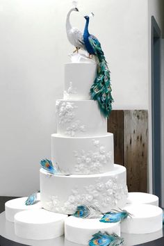 a large white cake with peacock decorations on it's top and bottom tiers