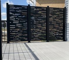 a black gate with wooden slats on the sides and brick walkway next to it