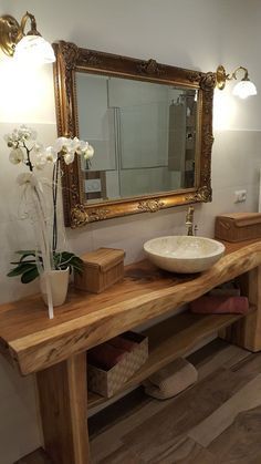 a bathroom with a sink, mirror and wooden counter top in front of a large gold framed mirror