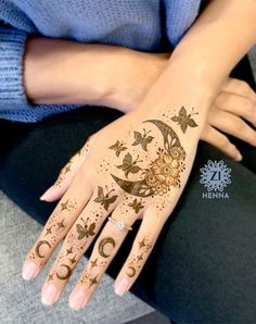 a woman's hand with henna tattoos on it and the moon and stars