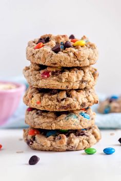 cookies stacked on top of each other with m & m in the middle and chocolate chips scattered around