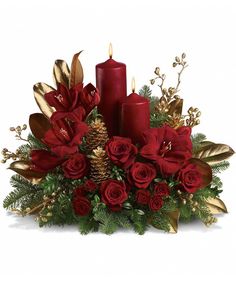 a christmas centerpiece with red candles and greenery, pine cones and evergreens