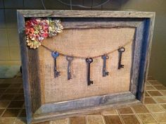 an old wooden frame with keys hanging from it's sides and flowers on the front