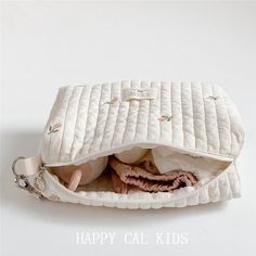 an open white purse sitting on top of a white table next to a stuffed animal