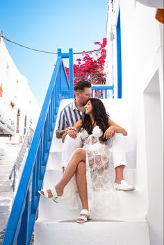 a man and woman sitting on the steps of a white building with blue railings