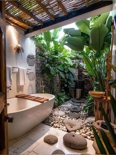 a bathroom with a tub, rocks and plants in the shower area that is surrounded by greenery