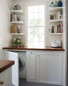 a washer and dryer in a small room with books on the shelves above