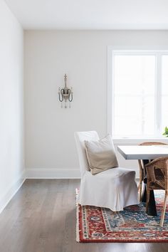 a dining room table and chairs with a rug on the floor in front of it