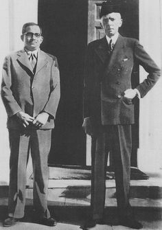 two men standing next to each other in front of a door with their hands on their hips