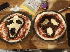 two pizzas sitting on top of pans covered in cheese and black olives