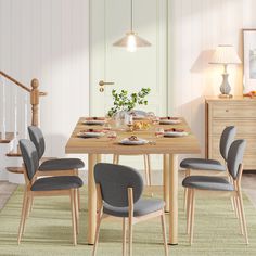 a dining room table set with grey chairs and plates on the placemat in front of it