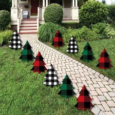 plaid christmas trees are lined up on the grass in front of a brick walkway and house