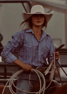 a woman wearing a cowboy hat and holding a lasso