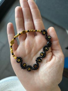 a hand holding a black and gold beaded bracelet in it's left palm