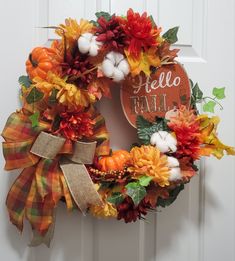 a fall wreath with pumpkins, cotton balls and burlocks hanging on the front door