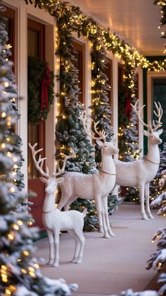 two white deer statues standing in front of a building with christmas lights on the windows