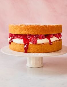 a cake sitting on top of a white plate covered in frosting and raspberries