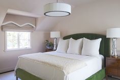 a bed with white pillows and green headboard