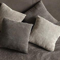 three black and white pillows sitting on top of a bed next to a pillow case