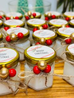 small jars filled with white and red christmas treats on top of a wooden table next to a potted plant