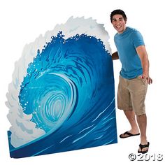 a man standing next to a large blue and white wave painting on the wall in front of him