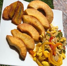 a white plate topped with sliced pineapples and scrambled eggs next to other foods